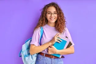 Smiling student holding books and a backpack
